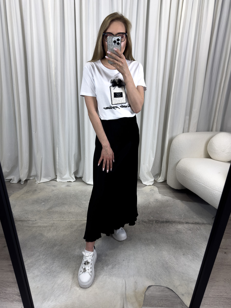 Spódnica Satine Black z połyskującej satyny w odcieniu klasycznej czerni, długość maxi, zestawiona z białym t-shirtem i białymi sneakersami – stylizacja na co dzień z nutą elegancji.