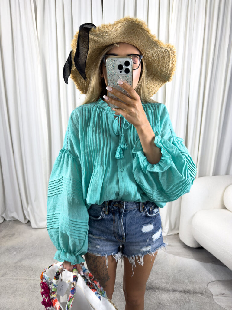 Zdjęcie produktowe sklepu internetowego z odzieżą damską – modelka ubrana w koszule Boho w kolorze turkusowym marki Wiya, jeansowe szorty oraz dodatki typu słomiany kapelusz, wiklinowa torebka koszyk