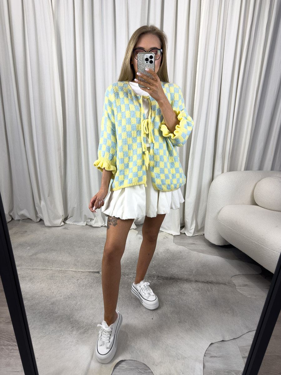 Zdjęcie produktowe sklepu internetowego z odzieżą damską – modelka w trampkach ubrana w kardigan Naomi żółty w print szachownicy i krótkie spódnico-spodnie