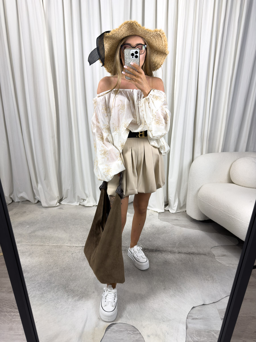 Zdjęcie produktowe sklepu internetowego z odzieżą damską – modelka w kremowej bluzce Neve Wiya z bufkami, plisowaną spódniczką i kapeluszem