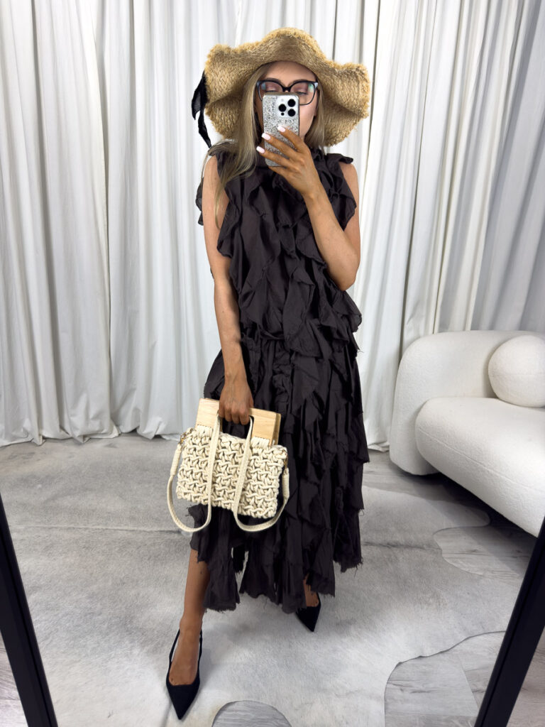 Komplet Milano z falbanami – kobieta w stylizacji z falbaniastym topem i długą spódnicą, trzymająca plecioną torebkę. Zdjęcie produktowe sklepu internetowego z odzieżą damską.