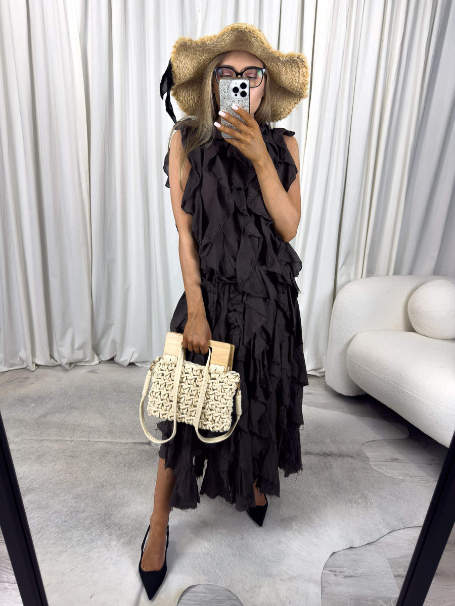 Komplet Milano z falbanami – kobieta w stylizacji z falbaniastym topem i długą spódnicą, trzymająca plecioną torebkę. Zdjęcie produktowe sklepu internetowego z odzieżą damską.