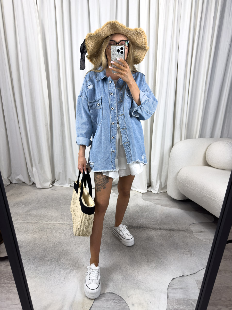 Zdjęcie produktowe sklepu internetowego z odzieżą damską – modelka w jasnej koszuli jeansowej Simple w stylu oversize, z białą sukienką i plecioną torbą