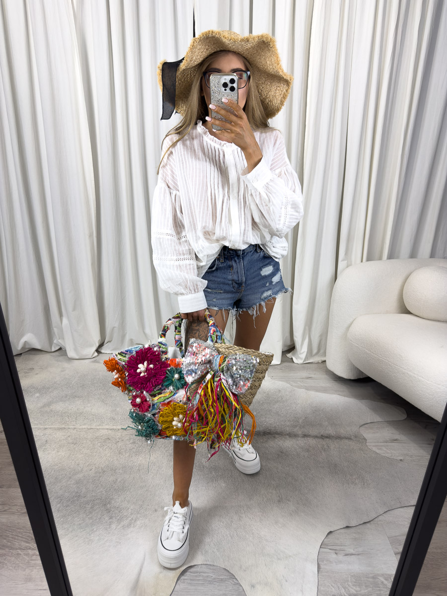 Zdjęcie produktowe sklepu internetowego z odzieżą damską – modelka w koszuli boho Luna marki Wiya, zestawionej z jeansowymi szortami, kapeluszem i wiklinową torbą