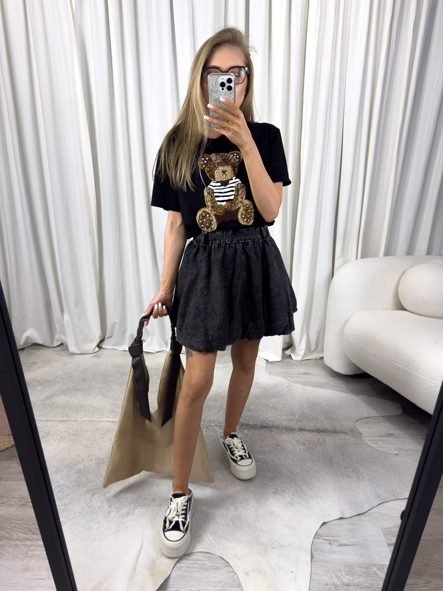 Zdjęcie produktowe sklepu internetowego z odzieżą damską – modelka w trampkach ubrana w t-shirt Teddy czarny, spódnicę w kolorze dekatyzowanej czerni trzymająca w ręce zamszową torebkę