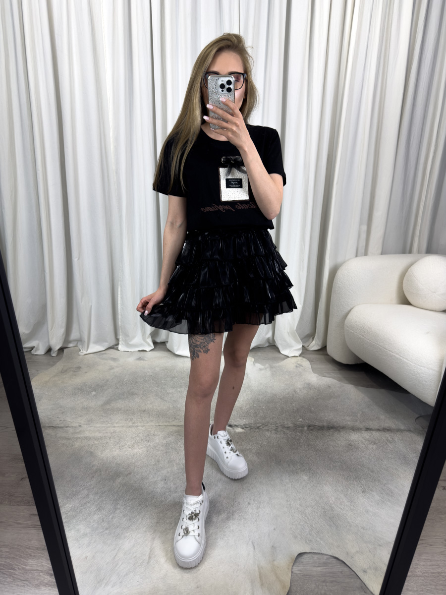 T-shirt Perfume czarny z aplikacją flakonika perfum i kokardką 3D, zestawiony z jasną spódnicą satynową – nowoczesna i elegancka stylizacja z nutą glamour.