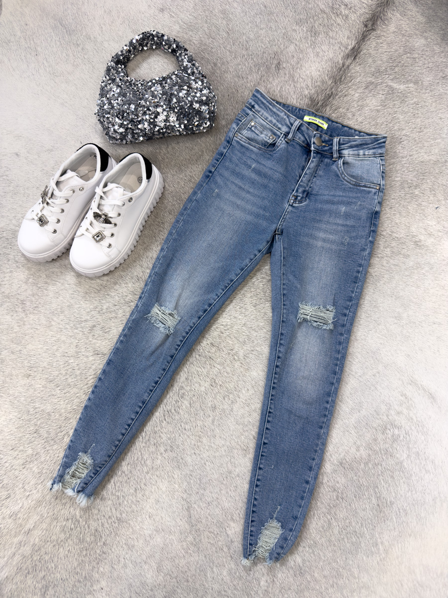 Spodnie jeansowe skinny Malibu – dopasowane niebieskie jeansy damskie z przetarciami i surowym wykończeniem nogawek, stylizacja z T-shirtem i sneakersami.