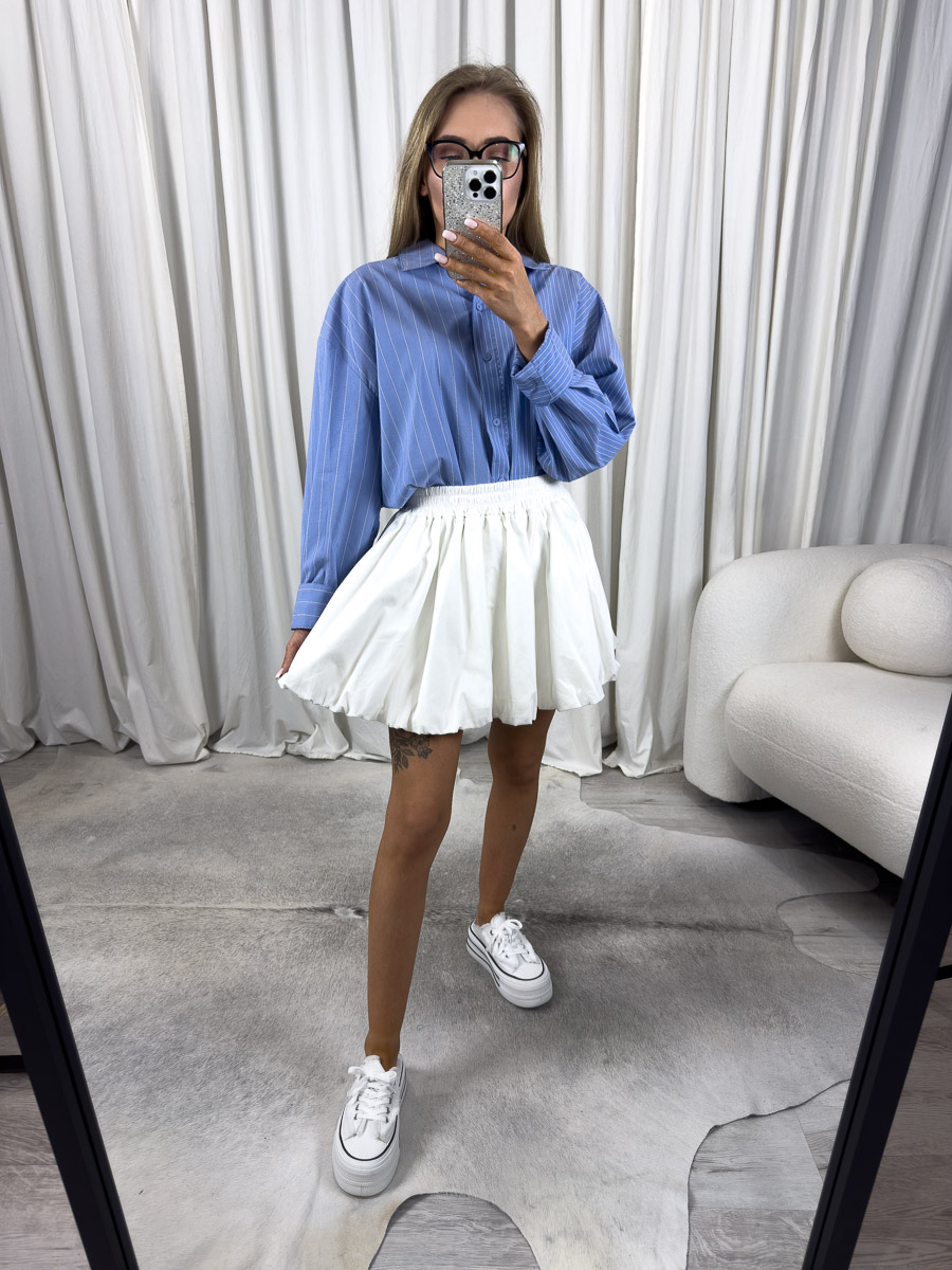 Zdjęcie produktowe sklepu internetowego z odzieżą damską – modelka ubrana w koszule popelinową Metro w kolorze granatowym w białe paski marki Wiya, spódnico-spodenki w kolorze białym oraz białe trampki