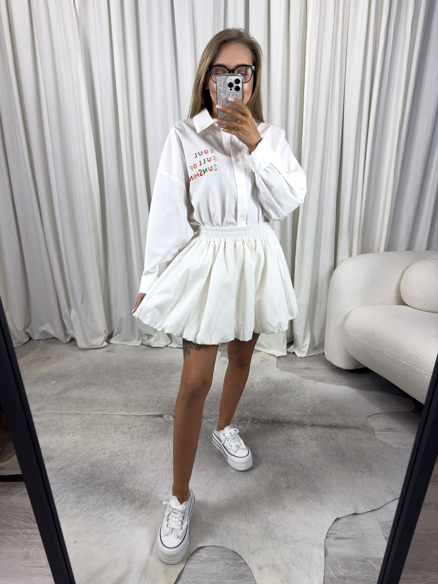 Zdjęcie produktowe sklepu internetowego z odzieżą damską – modelka ubrana w koszule popelinową Sunshine w kolorze białym marki Wiya, spódnico-spodenki w kolorze białym oraz białe trampki