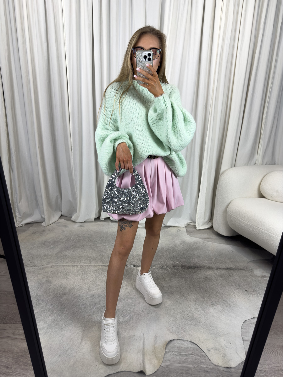 Kobieta w pastelowym swetrze Balloon Mint i różowej spódnicy mini, trzymająca cekinową torebkę – stylizacja wiosenna w stylu soft glam