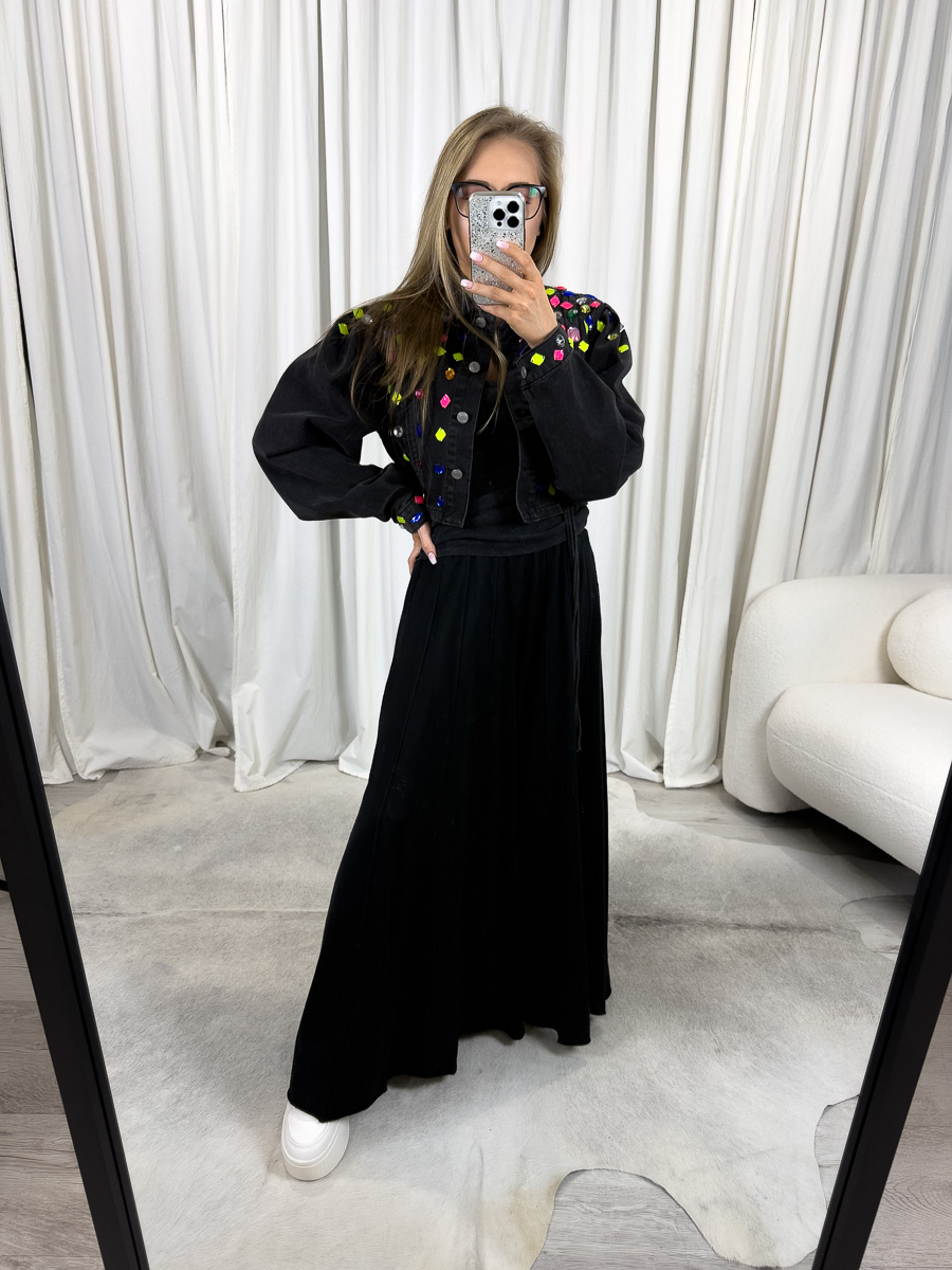 Modelka w spodniach dresowych Baggy Wiya czarnych, luźny krój z szerokimi nogawkami, stylizacja casualowa z białymi sneakersami na tle jasnych zasłon.