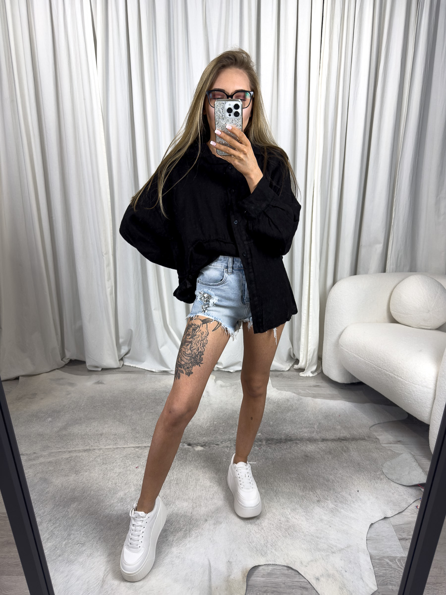 Czarna lniana koszula Lori od Wiya - luźny fason, naturalny len i asymetryczny krój z dłuższym tyłem. Stylizacja z jeansowymi szortami.