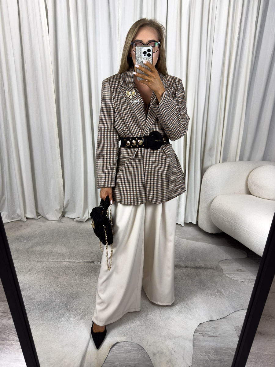 Modelka w marynarce o prostym kroju Glam z broszką i szerokimi spodniami. Zdjęcie produktowego sklepu internetowego z odzieżą damską.