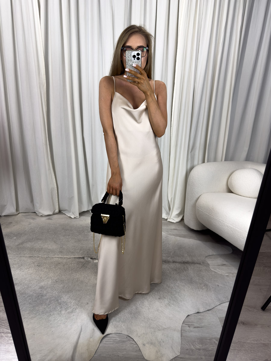 Modelka w sukience maxi satynowej Goldie na cienkich ramiączkach z dekoltem typu woda, długa kreacja w kolorze ecru, zestawiona z czarną torebką i szpilkami – zdjęcie produktowe do sklepu internetowego z odzieżą damską.